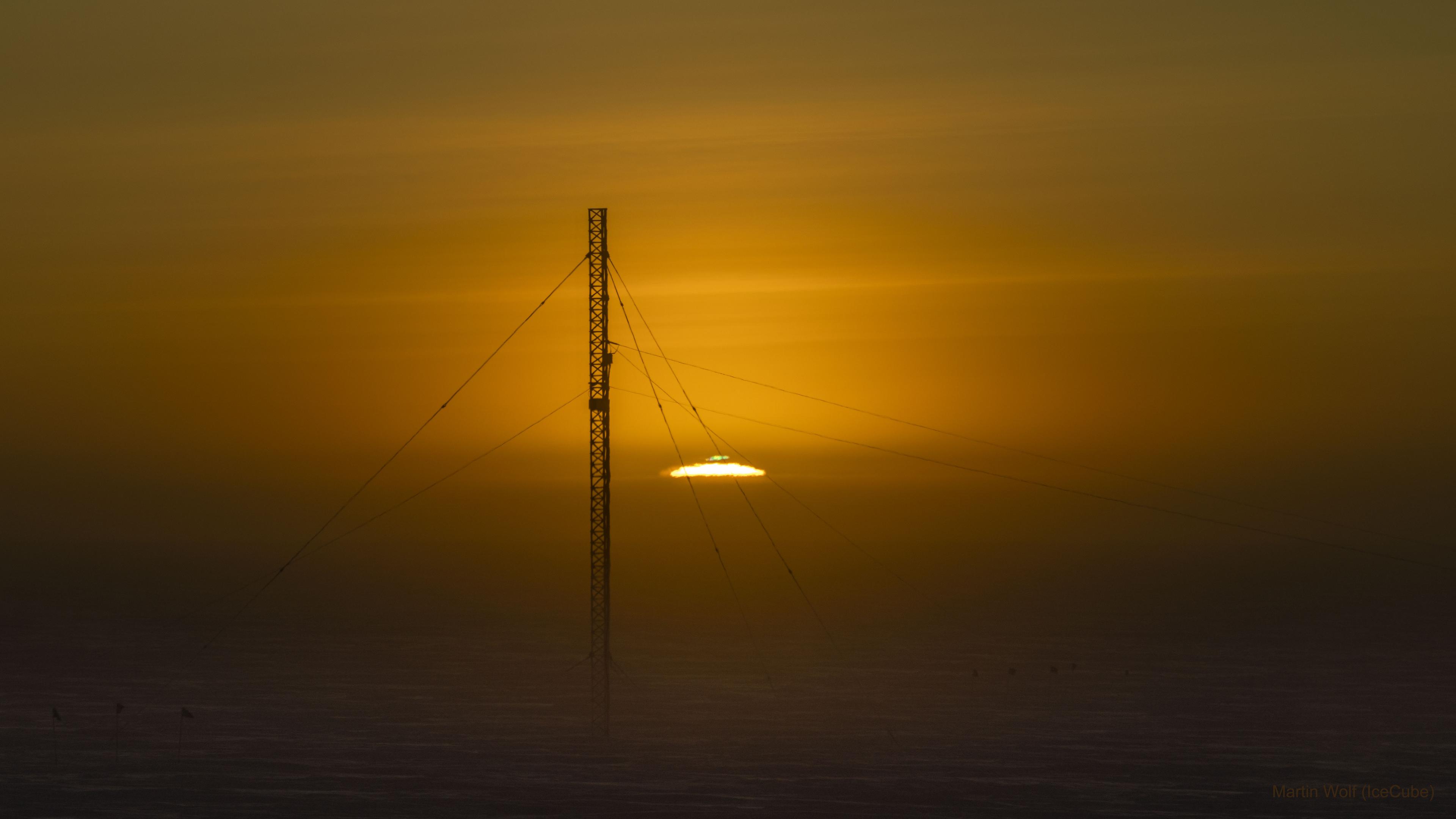شروق الشمس في الأسبوع الماضي في القطب الجنوبي خلال الاعتدال. يظهر برج اتصالات في مقدّمة الصورة، بينما تظهر الشمس وميضاً أخضراً في أعلاها.