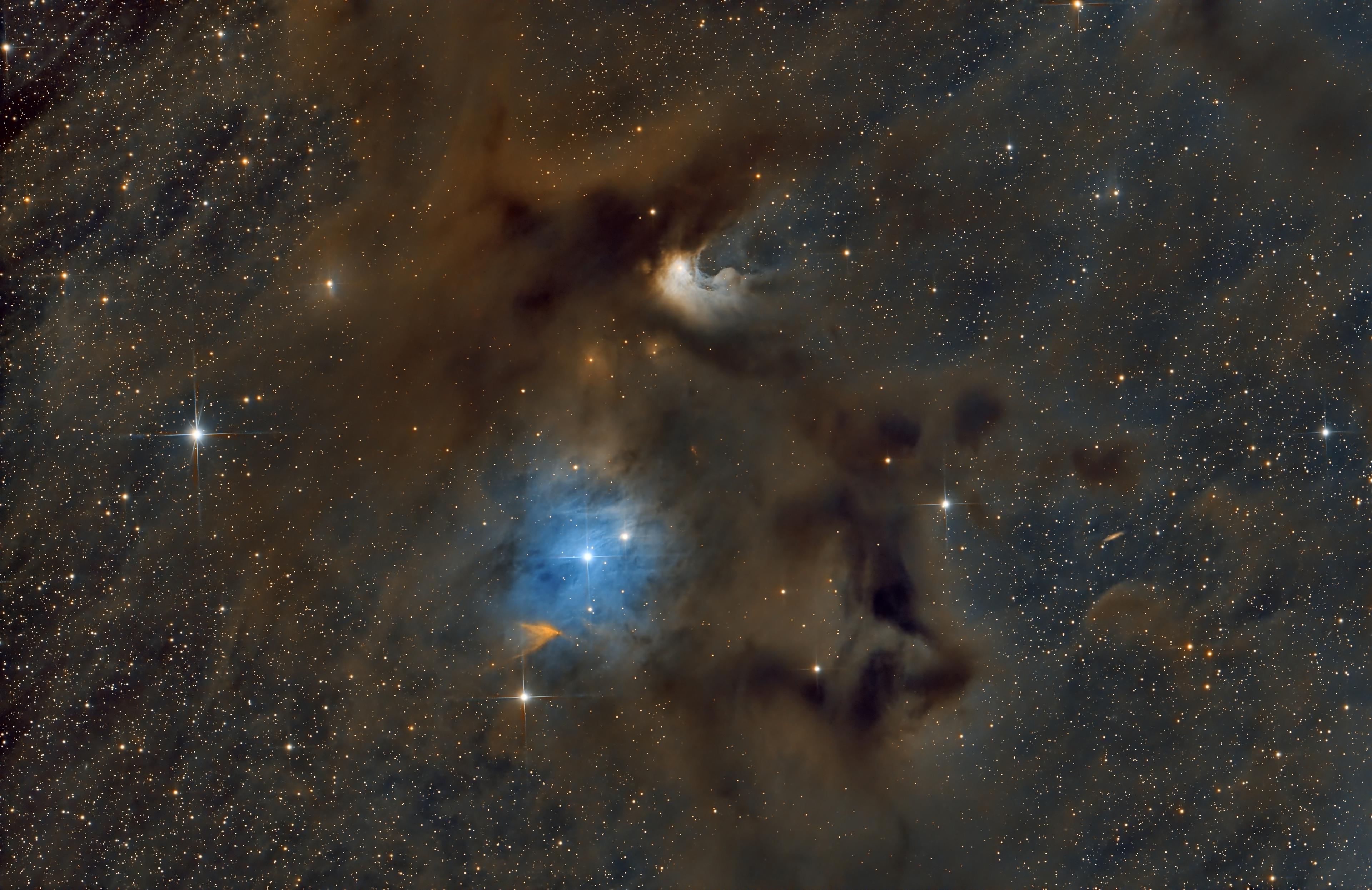 سُدم وأغبرة عاتمة بلون بني يتوسّطها منطقة ساطعة بلون أزرق مع تناثر نقاط النجوم المضيئة عبر الصورة