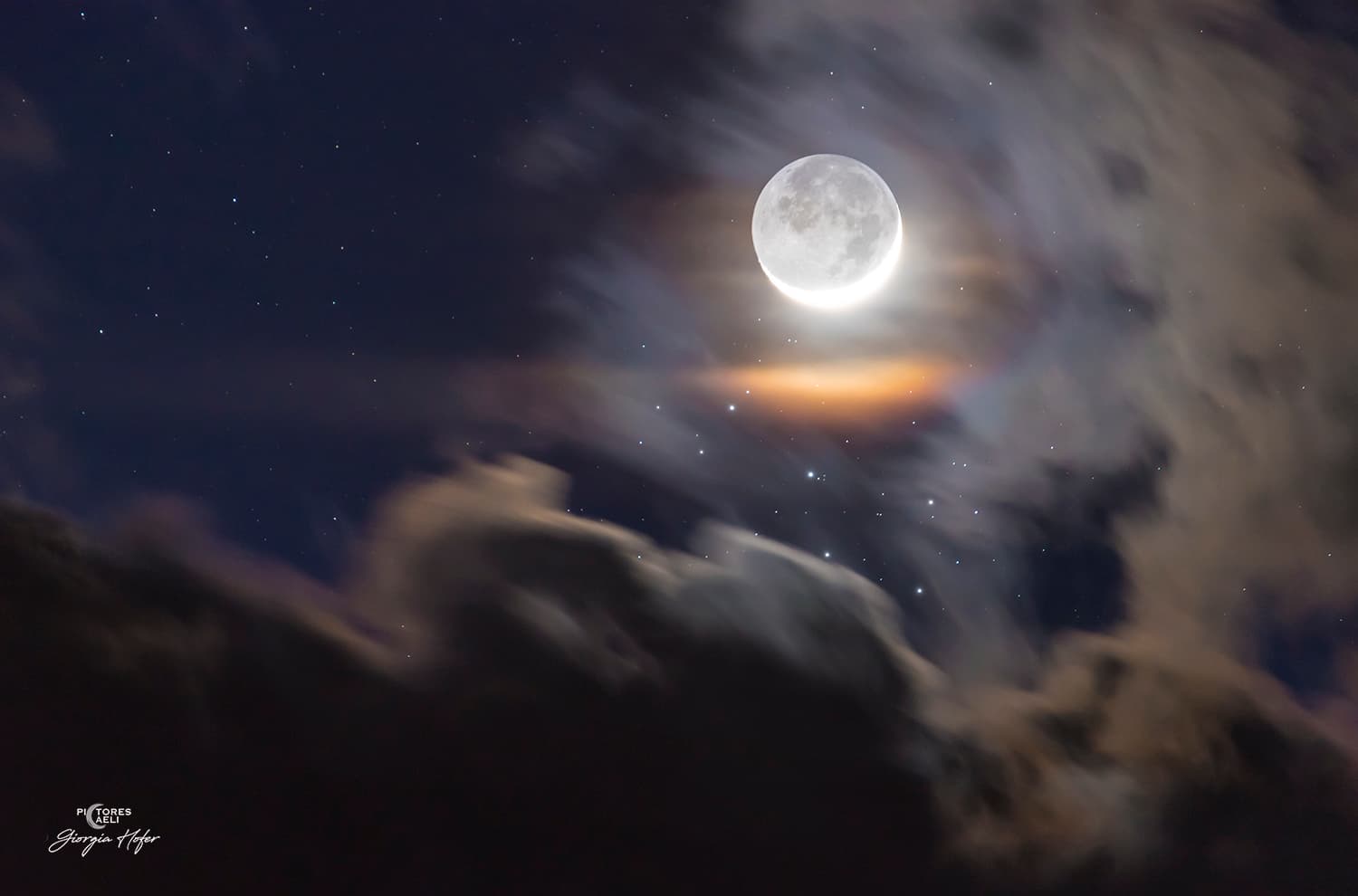 قرص القمر خافتٌ بالمعظم وعلى جانبه هلال يحيط به إكليل قمري ملوّن تتخلّله نجوم منها عنقود الثٌُّريّا مع امتداد غيوم على جانبَين من الإطار