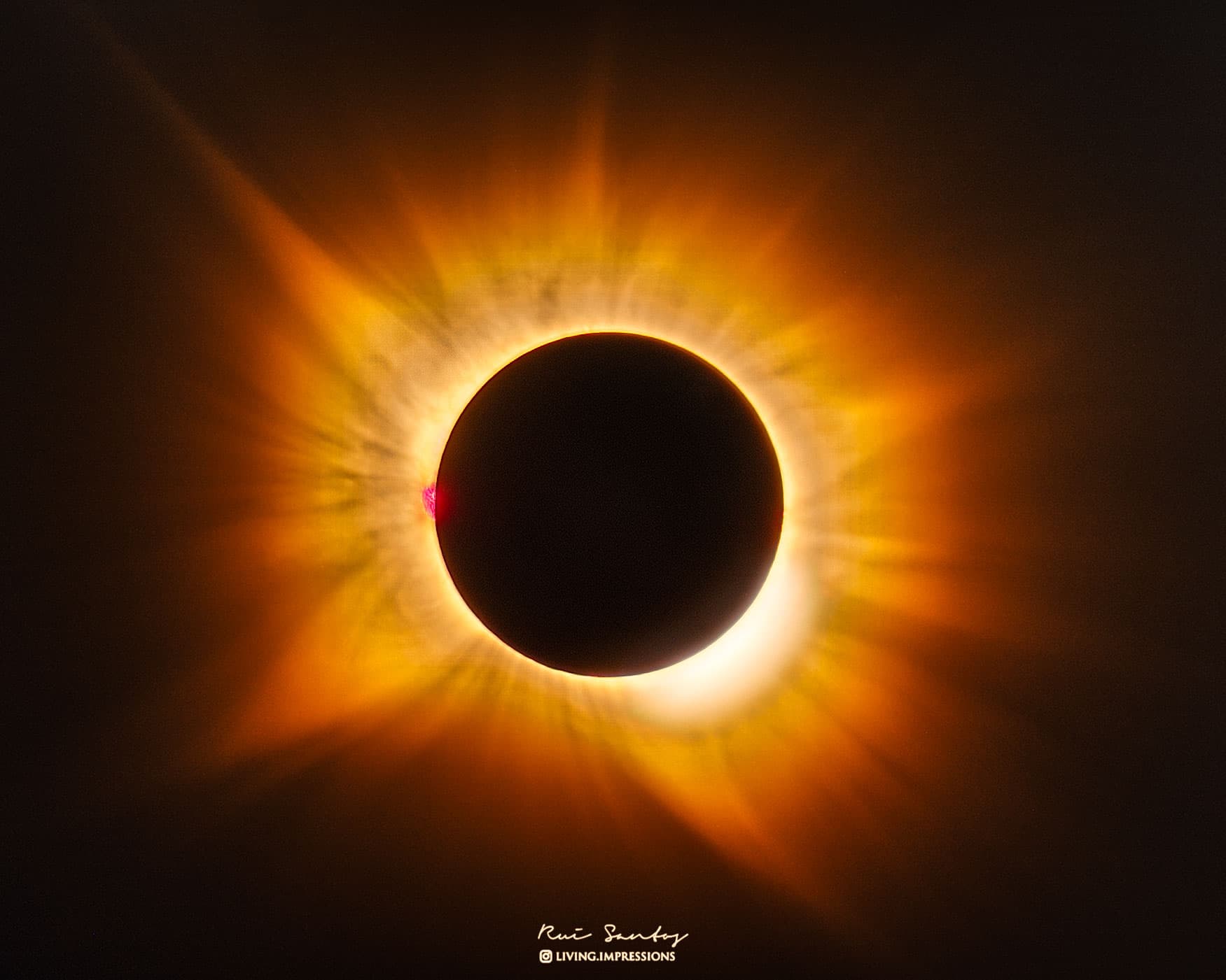 شمسُ كسوفٍ كُلّيٍّ في مركز الصورة وحولها إكليلٌ خيطيٌّ ذهبيّ اللون يتدفّق نحو الخارج في جميع الاتّجاهات