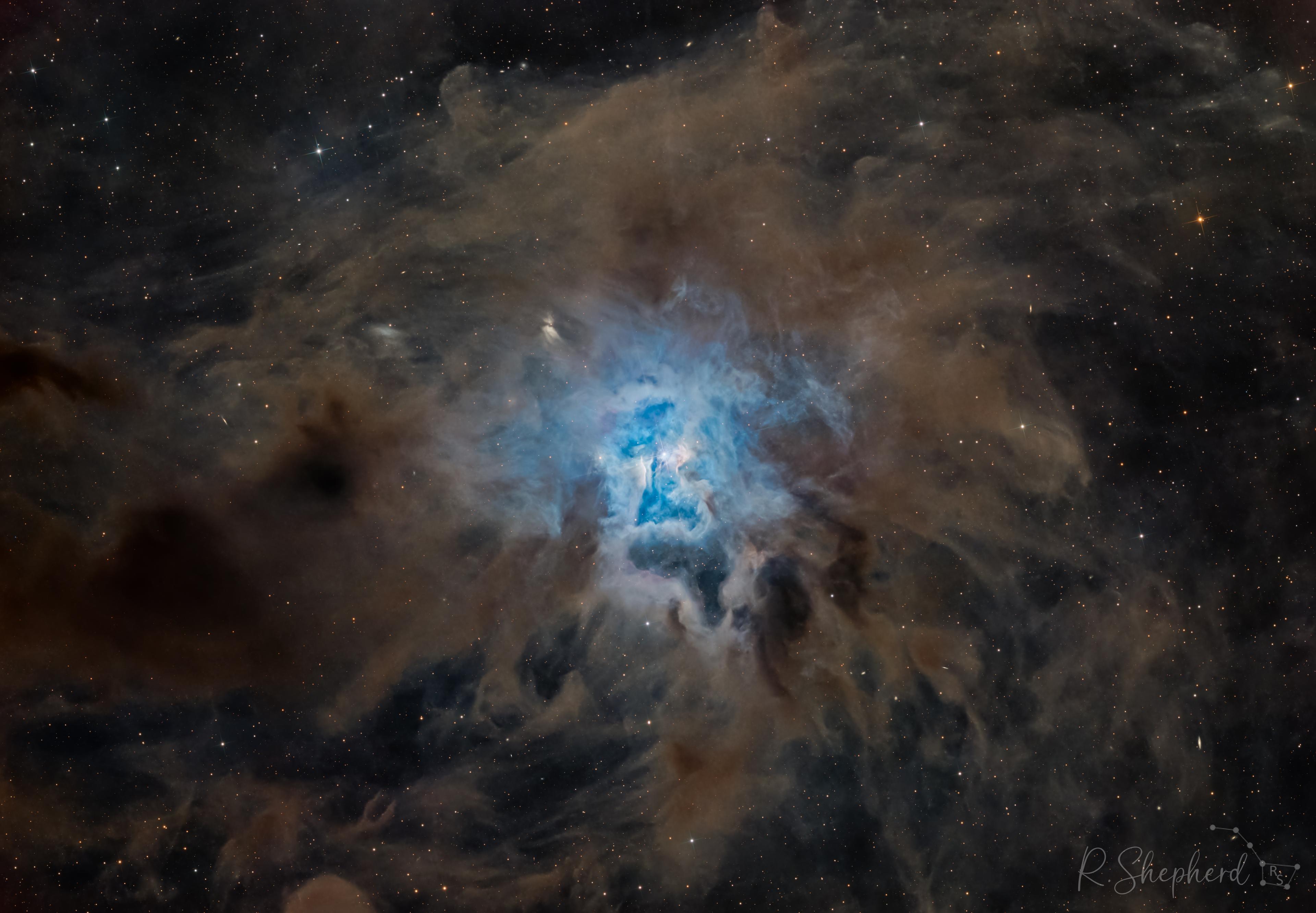 سديمٌ بامتدادات مغبرّة تبرز في وسطه منطقة ساطعة بيضاء مزرقّة وتحيط بها أغبرة عاتِمة. تظهر نجوم متفاوتة عبر الصورة.