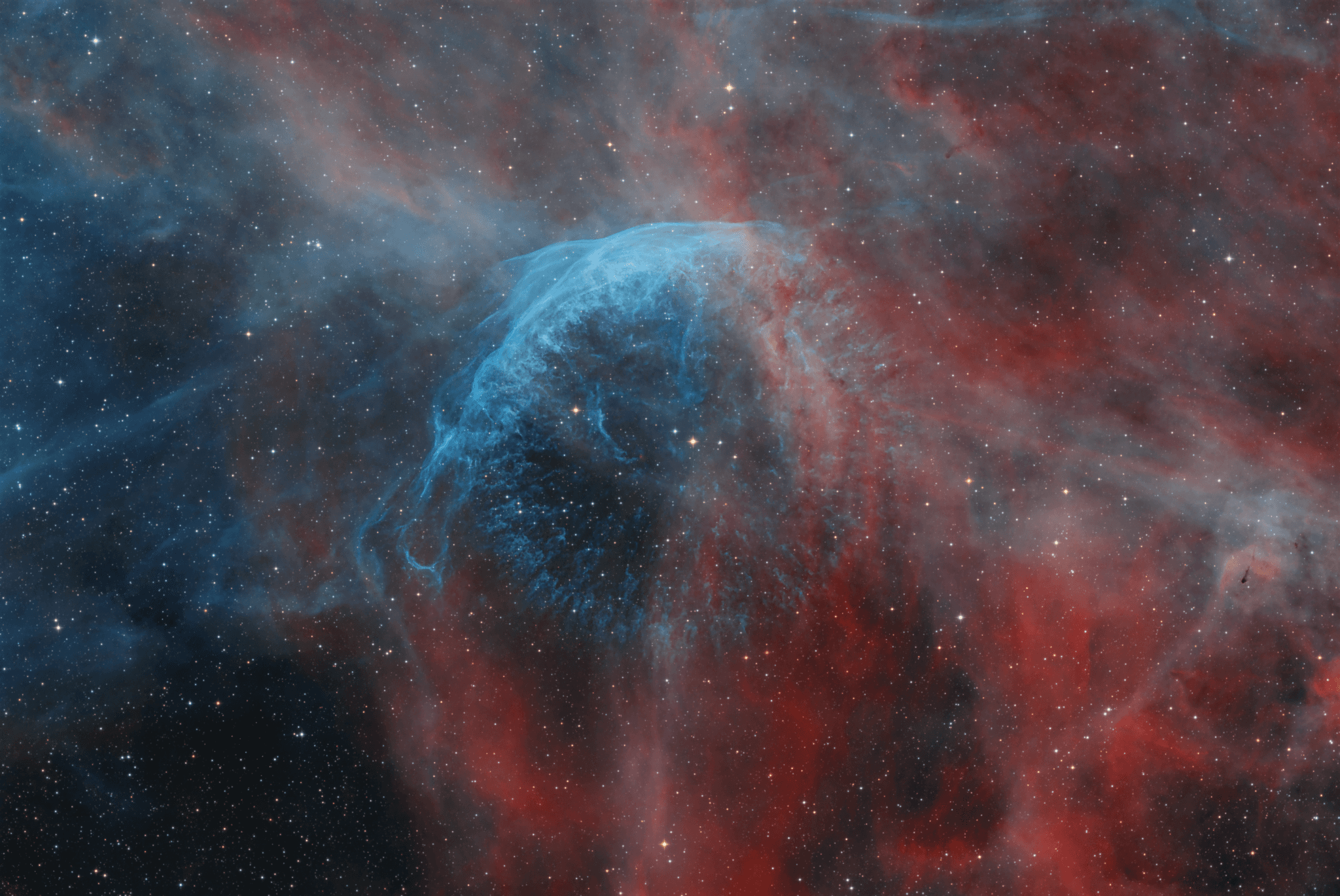 شبه فقاعة بلون مزرقّ وحولها امتدادات محمرّة بمُعظَمِها بينما تتناثر نجوم عبر الصورة