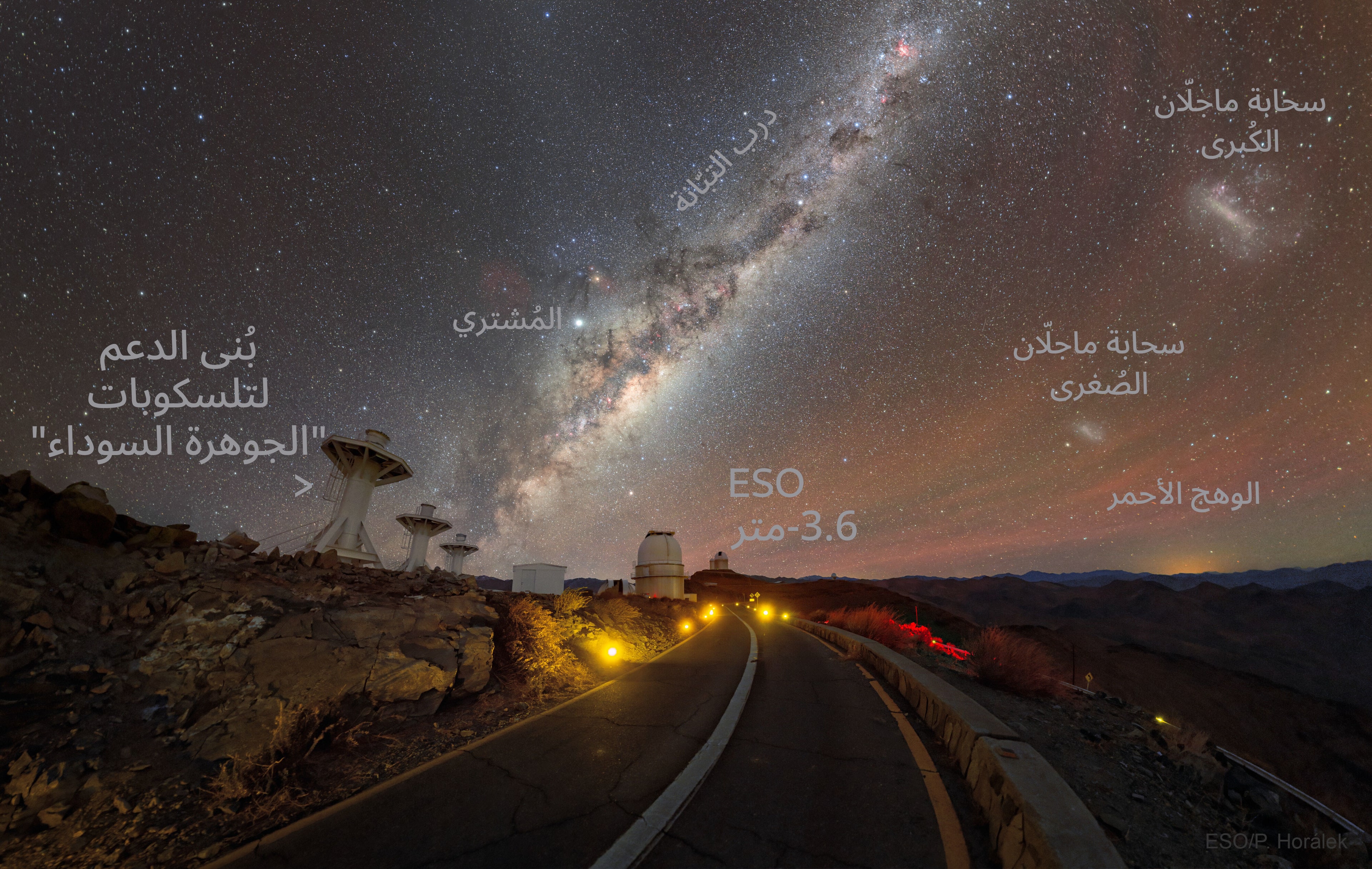 نسخة معنونة من الصورة وضّح عليها مكان بنى دعم تلسكوبات الجوهرة السوداء على اليسار وتلسكوب المرصد الأوروبي الجنوبي ذو الـ3.6 متر في المنتصف وفوقه نطاق درب التبّانة والمشتري أعلى منتصفه وأعلى اليمين سحابة ماجلّان الكبرى وتحتها الصغرى بينما يمتدّ الوهج الأحمر على اليمين كذلك