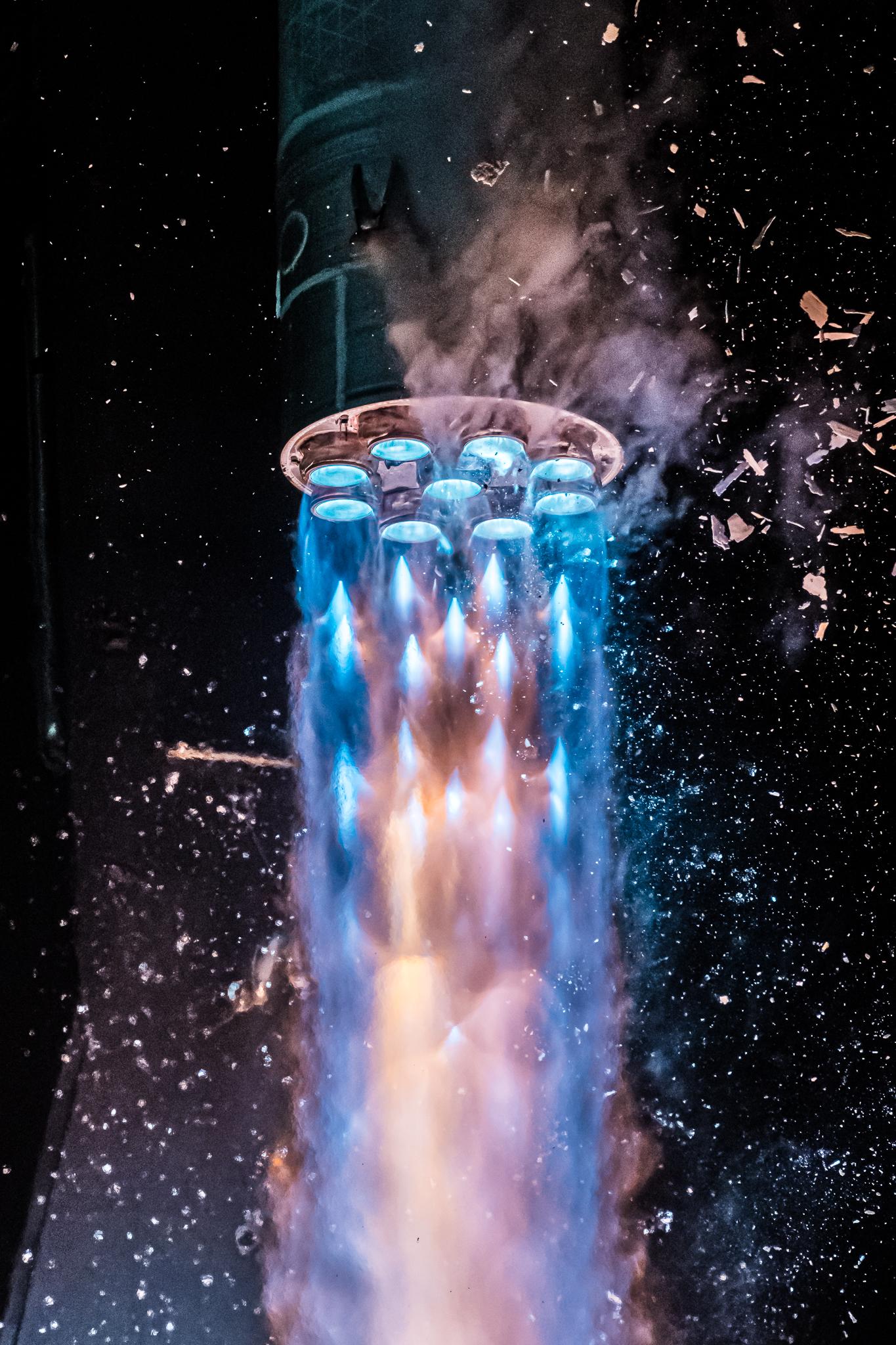 صاروخ منطلق وتظهر فوّهات تسع أسفله تنفث مادّة زرقاء بينما تتناثر أشياء حوله