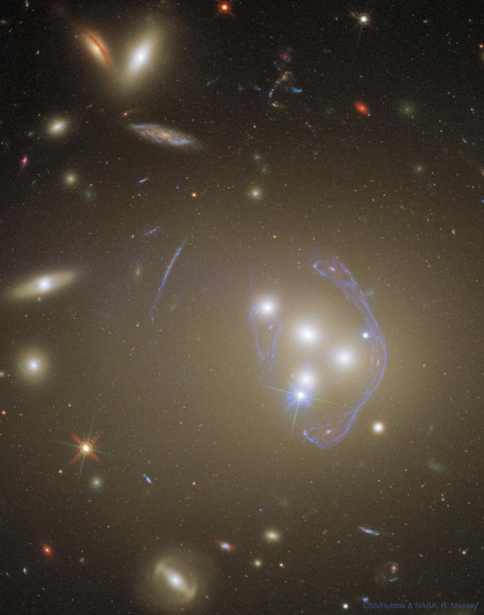 تُظهر الصورة العنقود المجري أبِل 3827 كما التقطه تلسكوب هَبل. يمكن رؤية مجرّات العنقود كما بالإمكان رؤية صورة معقّدة ومضاعفة لمجرّة في الخلفية حيث يكون العنقود بمثابة عدسة ثقالية.