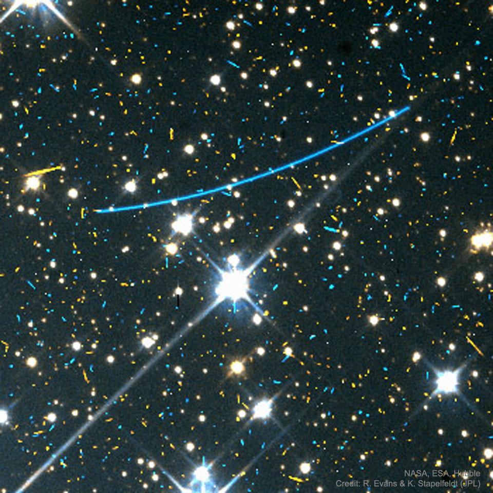 صورة تظهر كويكباً يمرّ في إطار صورة التقطها تلسكوب هَبل الفضائي، حيث يظهر كخطّ أزرق طويل ومن خلفه وحوله نجوم وأجرام بألوان زرقاء وصفراء وبيضاء