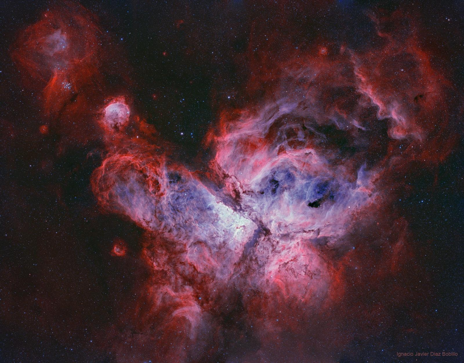 بنية سديميّة تظهر كإندفاعات من نقطة مركزية بألوان بيضاء فزرقاء فحمراء وحوله بعض النجوم