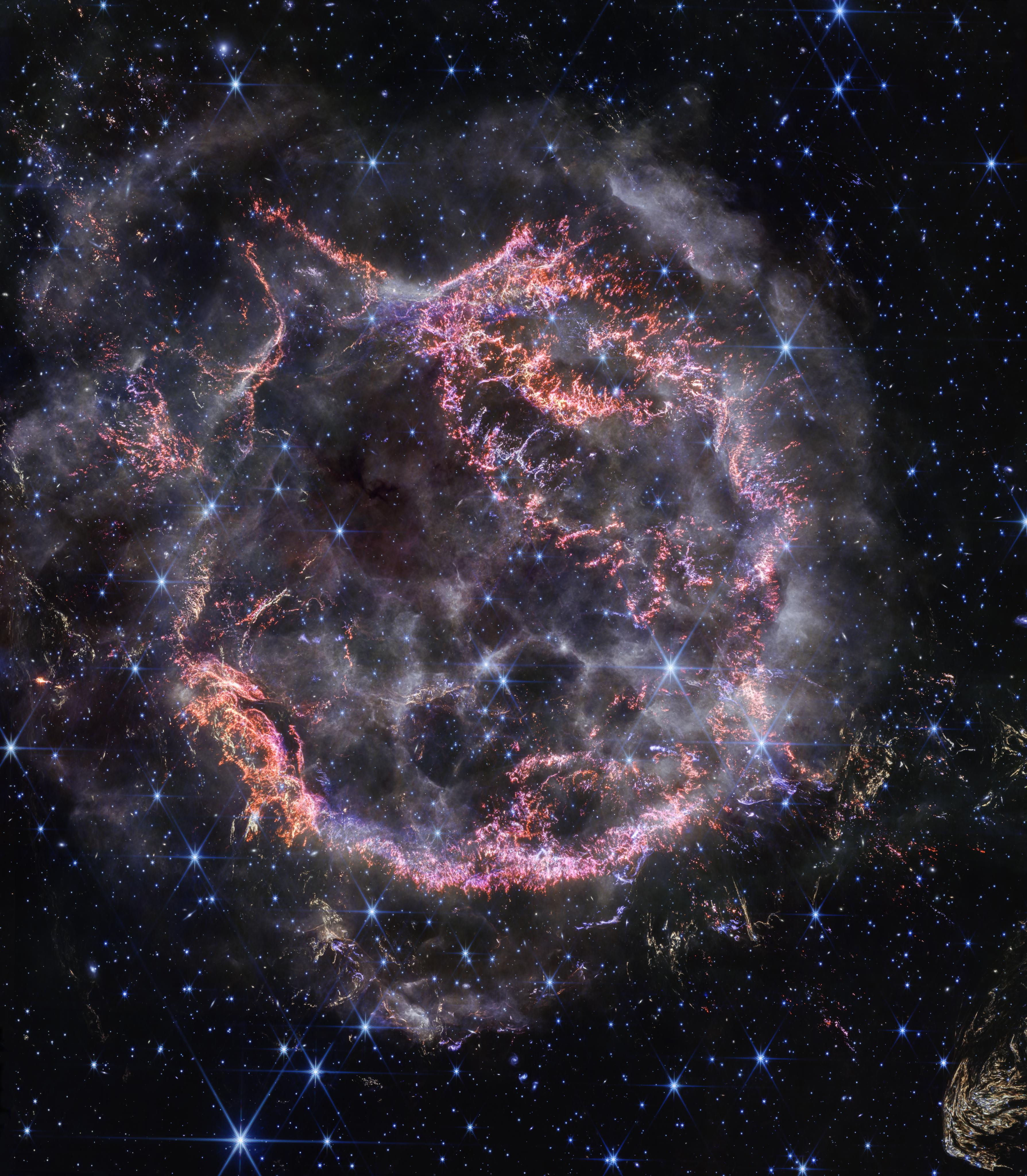 هيكل من الخيوط التي تظهر كدائرة متوسّعة بألوان محمرّة قاسية بمعظمها، يحيط بها ويتخلّلها أغبرة دخانيّة بيضاء، في حين تظهر نجوم كبيرة ذات أشواك سداسية وأخرى نقطيّة