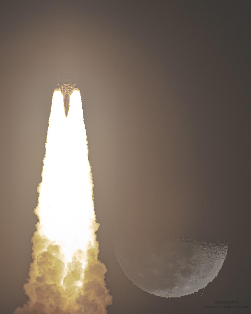 اندفاعات ملتهبة من فوّهات صاروخ مع أدخنة وبجانبها القمر الذي تبدو أطرافه كأنها شمع يذوب
