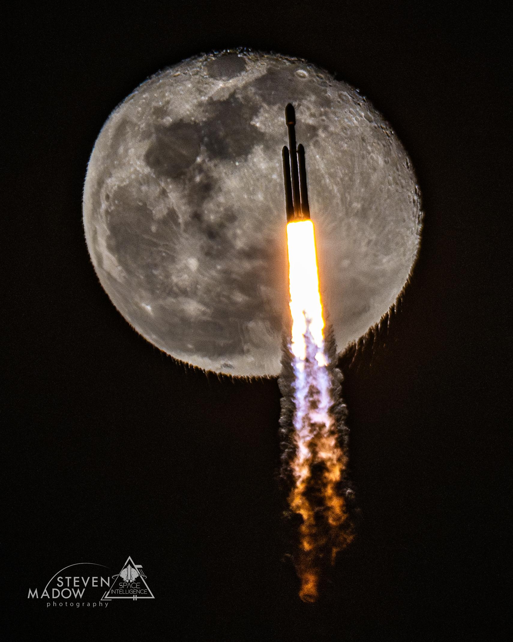 صاروخٌ آخذٌ بالصعود أثناء الإطلاق، وقمرٌ شبه مُحتملٍ خلفه. يسبّب عادم الصاروخ، المرئيّ بحدّ ذاته، أن يبدو أسفل القمر متموِّجاً على نحوٍ غير مُعتاد.