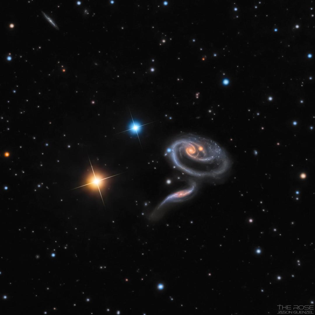 مجرّتان متفاعلتان بمظهر عجيب جيث تبدو إحداهما بشكل حلزوني بينما الأخرى تظهر بشكل مائل أسفل منها، بينما تنتشر النجوم على امتداد الصورة وإثنان منهما كبيرتان مدببتان