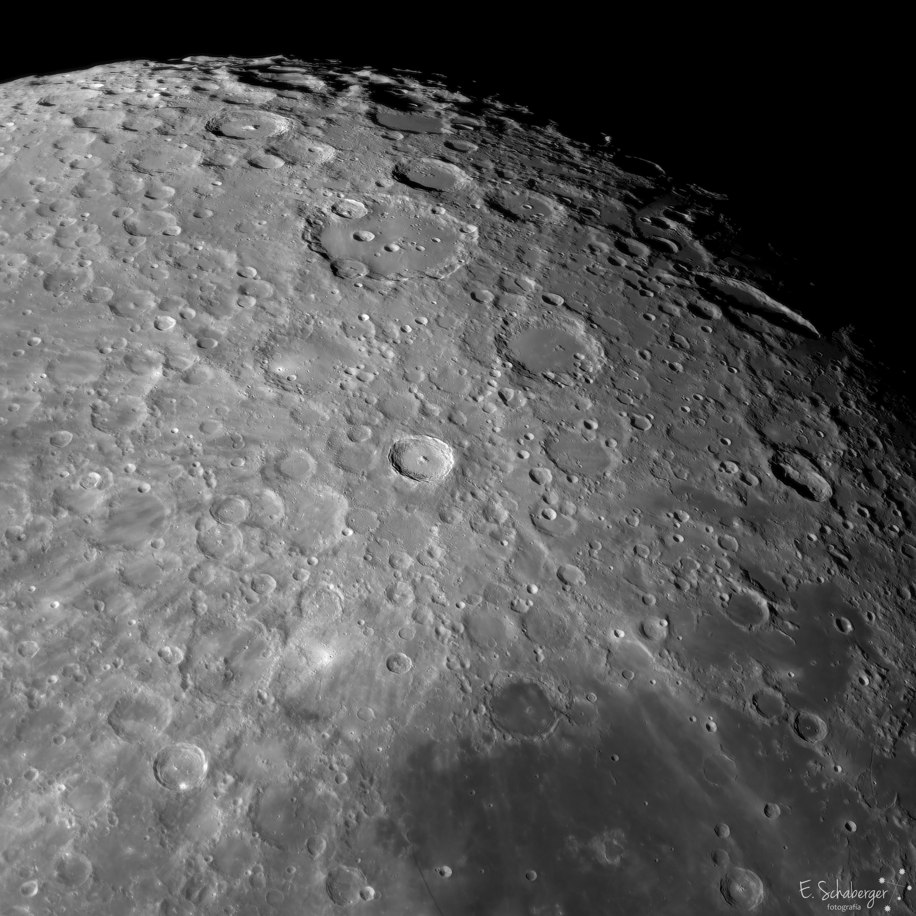 صورة مقرّبة لسطح القمر تظهر فوّهة تيخو بالأشعّة المنبثقة منها وفوّهة كلاڤيوس الملساء إلى الأعلى منها.