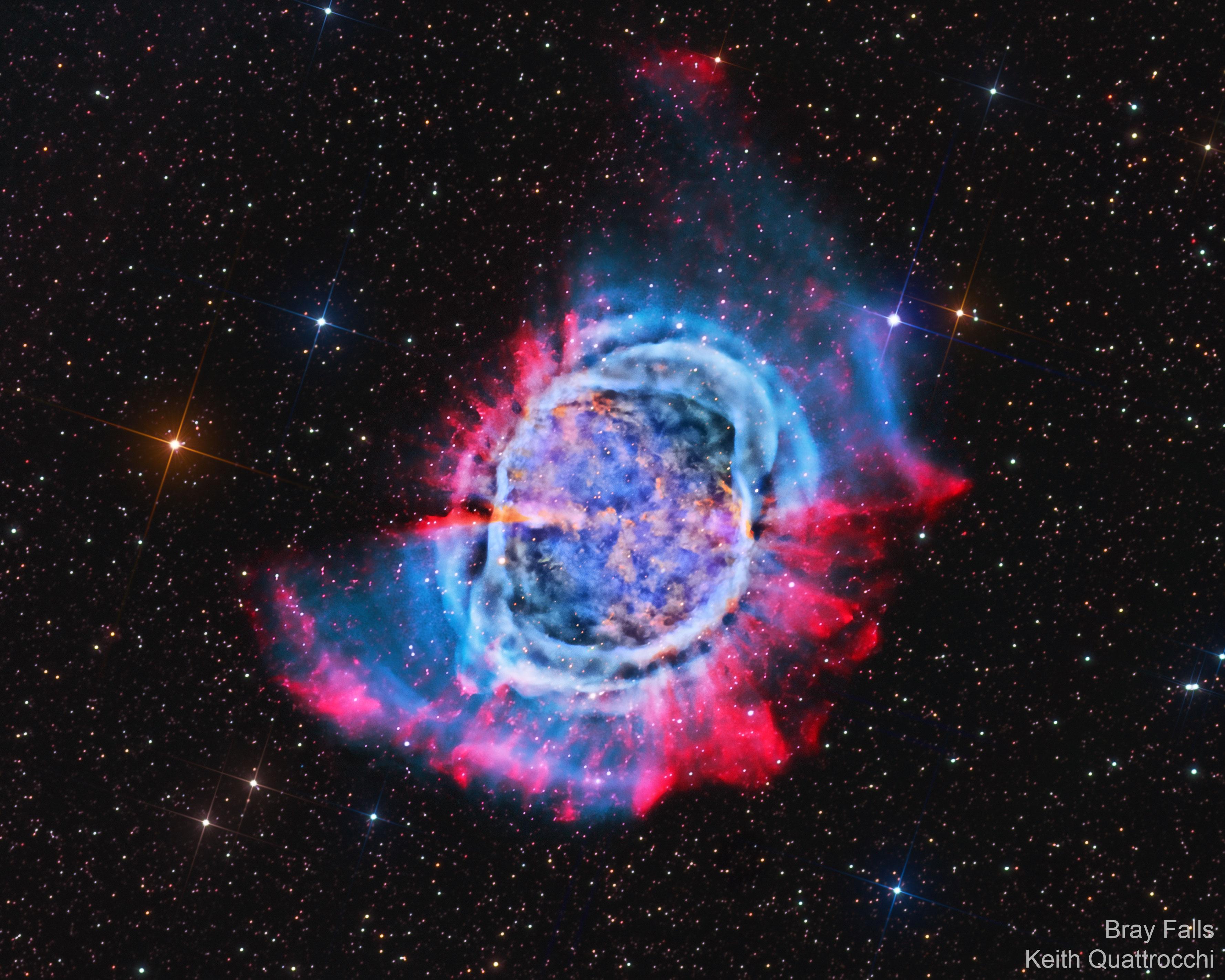صورة لسديم كوكبي في الفضاء العميق، وحوله دائرة غازية باللونين الأحمر والأزرق وتظهر حوله النجوم.