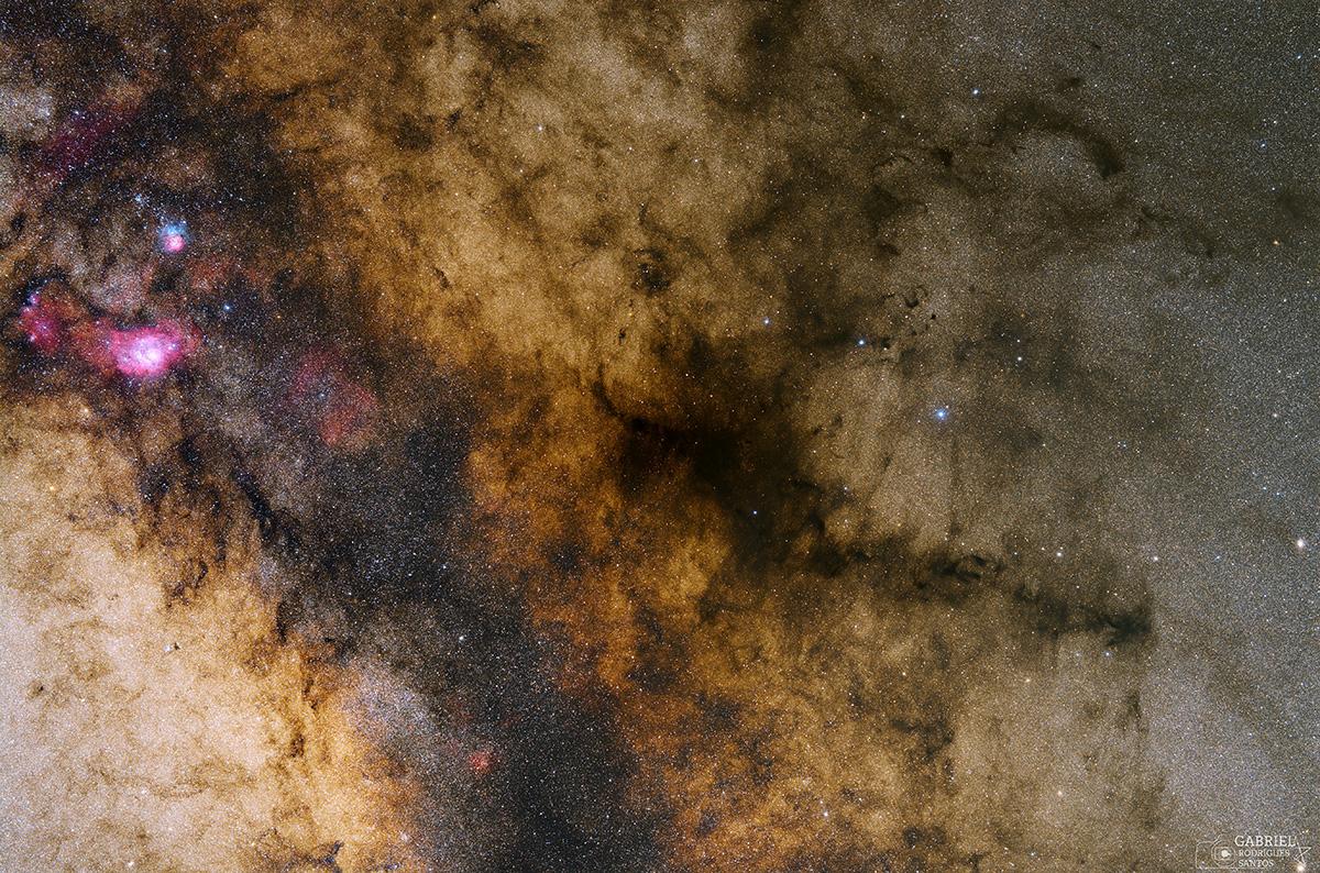 صورة للفضاء العميق تُظهر سدماً وسحباً ملونة ومناطق داكنة في مركز مجرّتنا درب التبانة.