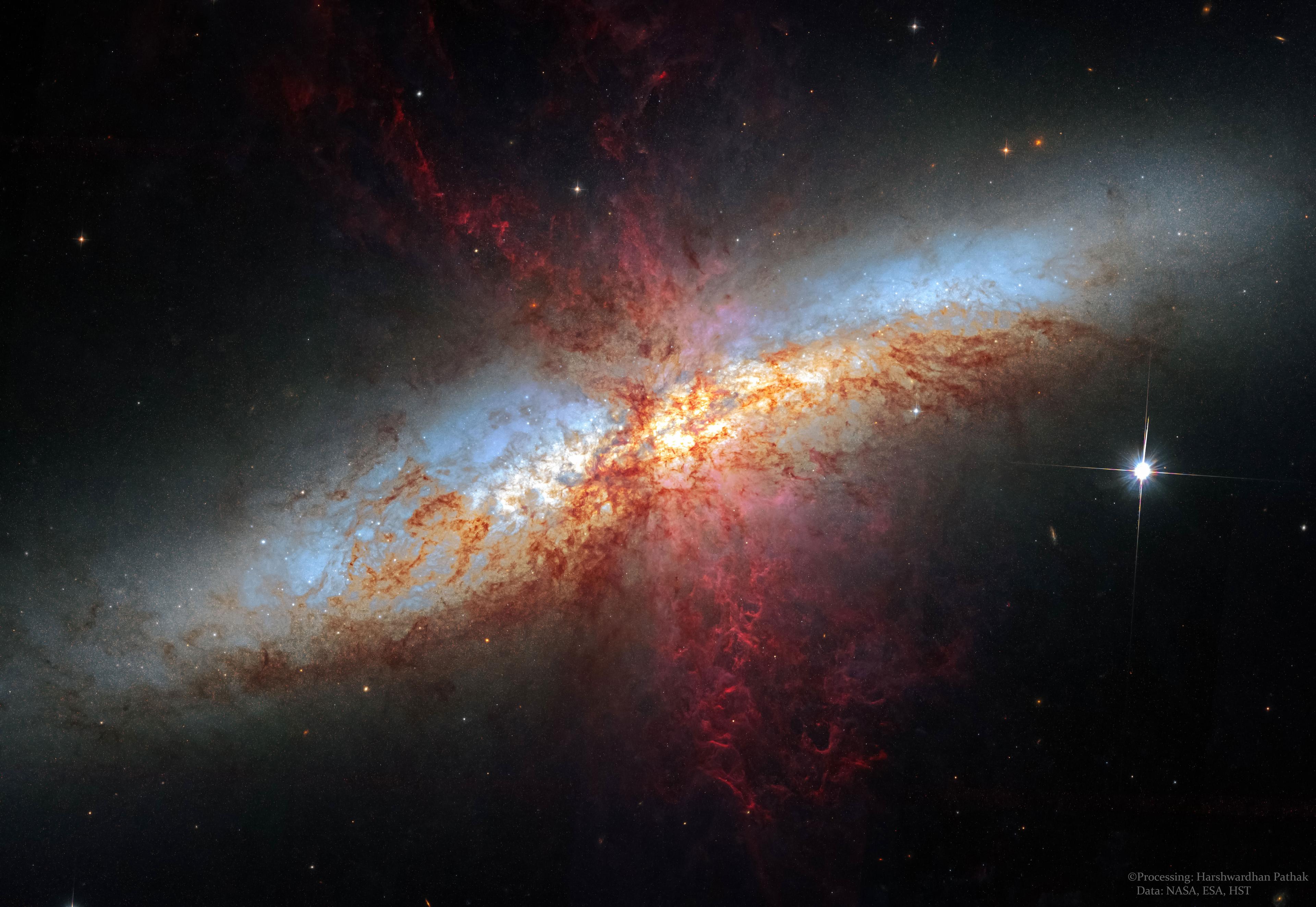 تظهر المجرّة الحلزونيّة مع الكثير من الخيوط الحمراء المُعقّدة مُمتدّة للخارج.