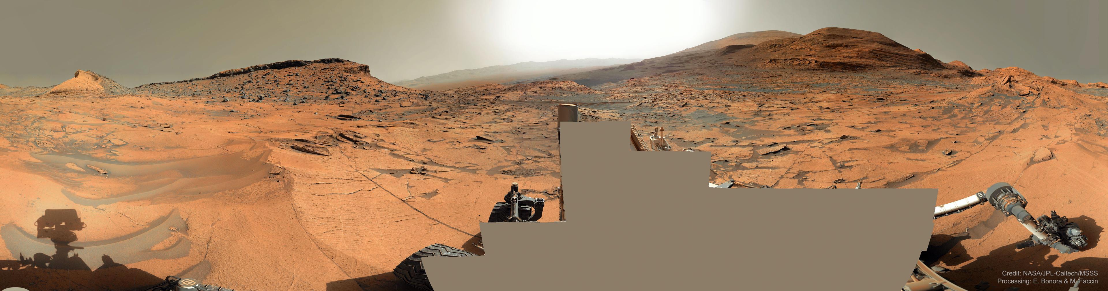بانوراما لسطح المرّيخ تظهر أرضه الصخرية الحمراء وتلاله ذات الطبقات ورماله الرمادية المنجرفة وغلافه الجوّي الأغبر.