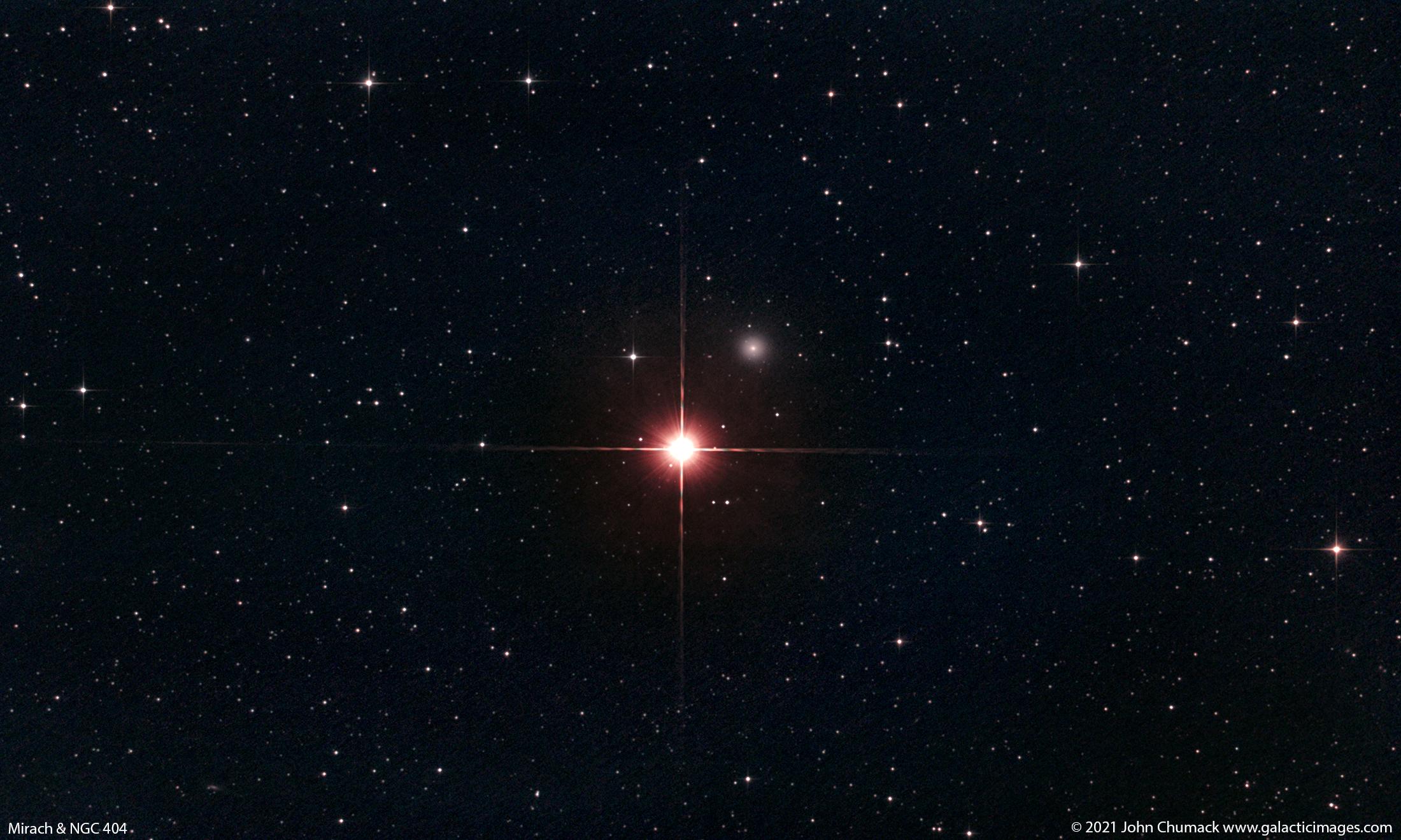 صورة للفضاء العميق تُظهر نجماً ساطعاً ذو انحرافات ضوئية مدببة بالإتجاهات الأربع، بينما تظهر مجرّة زغباء صغيرة بقربه على أعلى اليمين، بينما تتناثر العديد من النجوم على امتداد الصورة