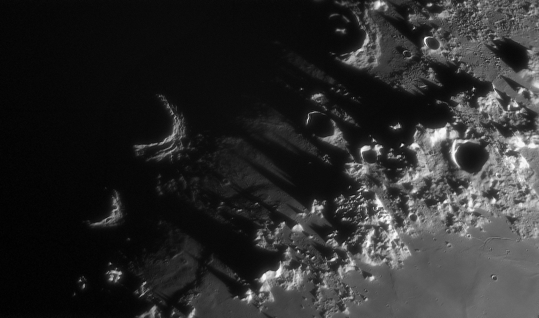 تضاريس من مرتفعات تُلقي بظلالها يساراً وفوّهات مختلفة الأحجام بجدران تعكس بعض الضوء وقيعان مظلمة