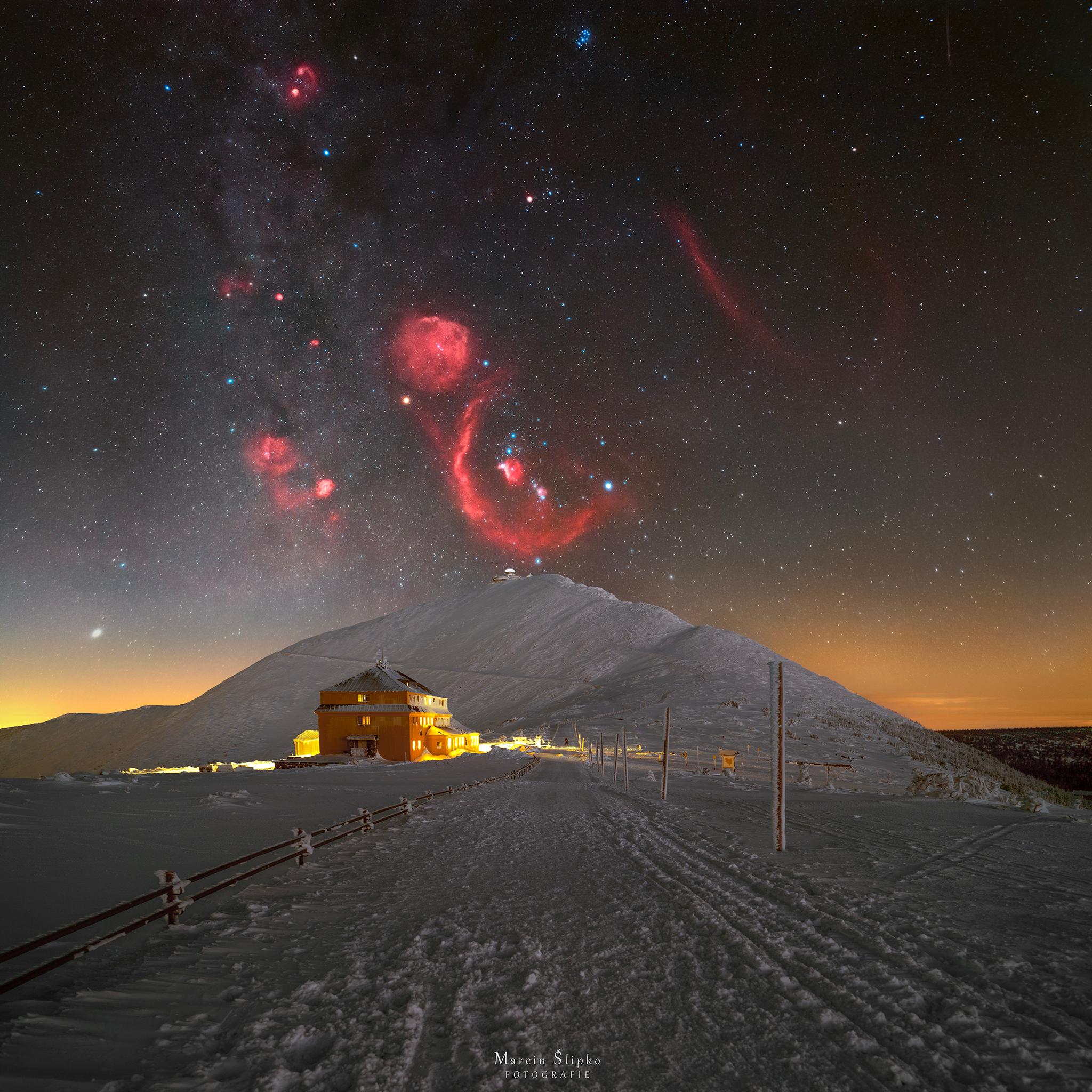 مشهدٌ طبيعيّ ثلجيّ مع تلَّةٍ كبيرة في المُنتَصَف. يوجد فوق التلّة حقل نجومٍ تظهر فيه نجوم وسُدُم كوكبة الجبّار، مع الوهج الأحمر السُّدُم في تبايُنٍ صارخ مع للسماء المُظلِمة والثلج الساطع.