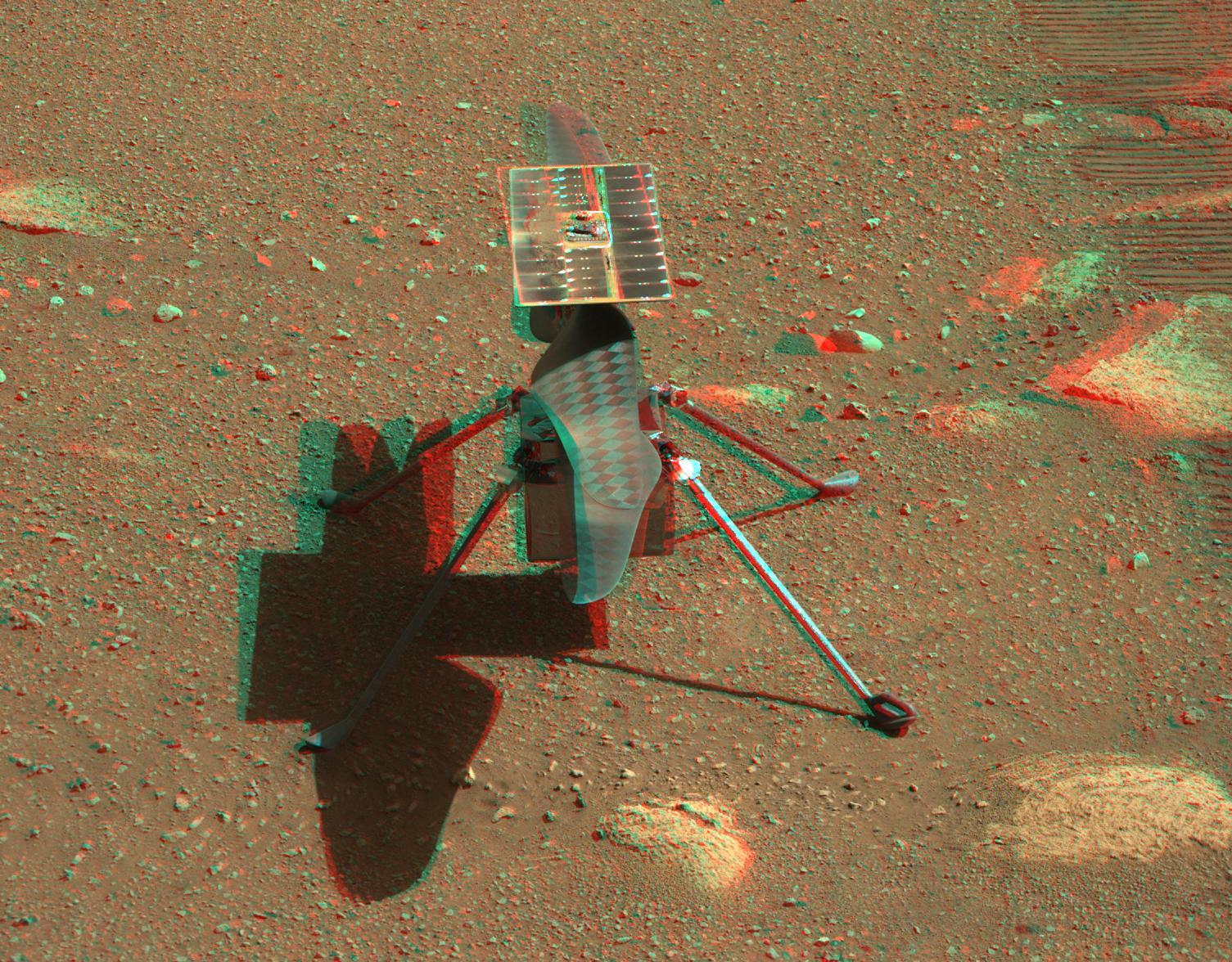 صورة مجسّمة تستهدف النظارات الحمراء/الزرقاء لمروحيّة البراعة المرّيخية، تظهر فيها المروحيّة ملقيةً بظلالها على السطح المرّيخي لوحدها على أرجل هبوطها الأربعة قرب مسارات العربة الجوّالة، وفي أعلاها لوح شمسي وتحته زوج شفراتها متضادّة الدوران التي طولها 1.2 متر