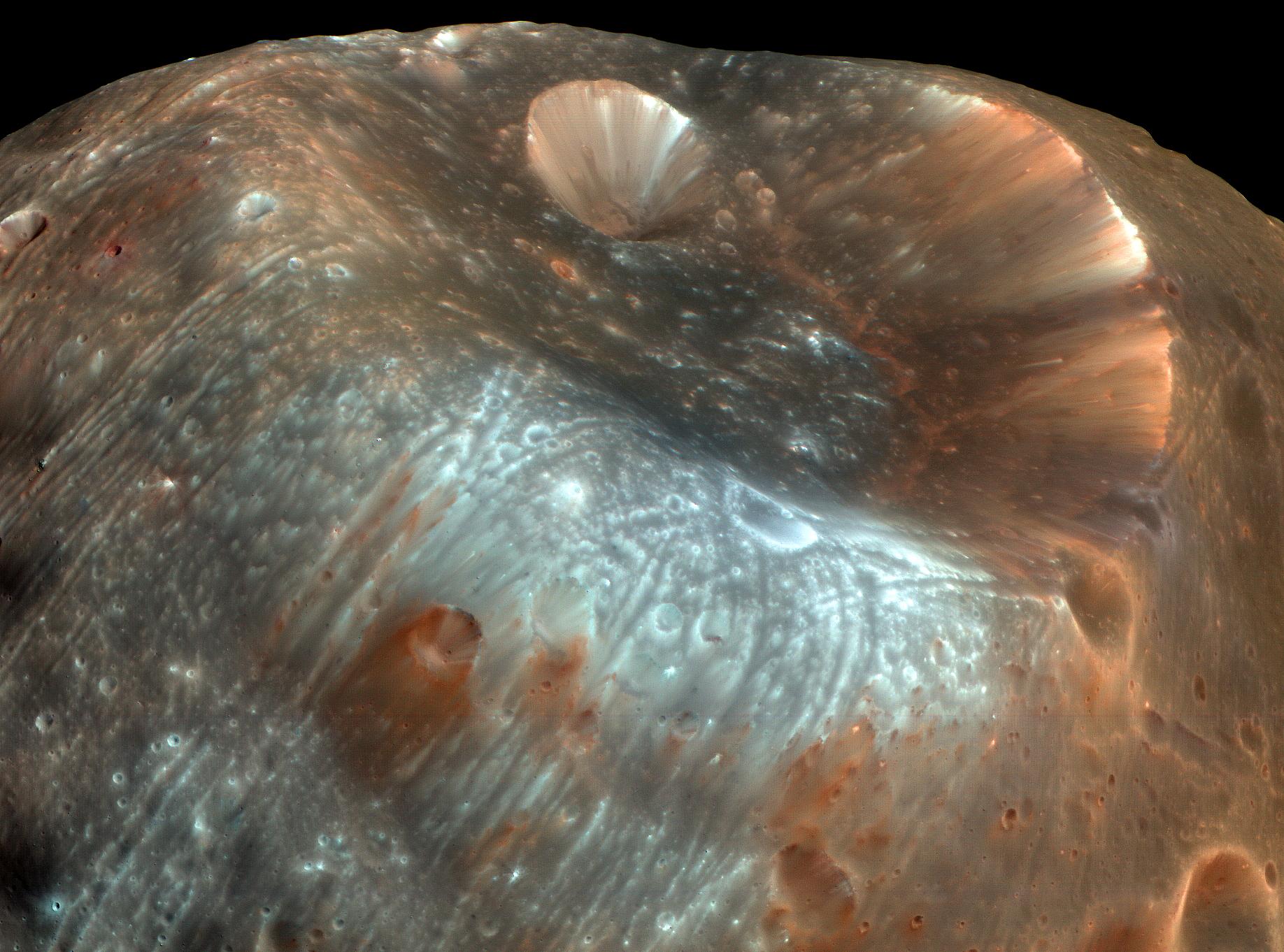 جزء من سطح قمر فوپوس غريب الشكل يُظهر فوّهة ستيكني وبعض التضاريس المحيطة بألوان معدنيّة تقريباً