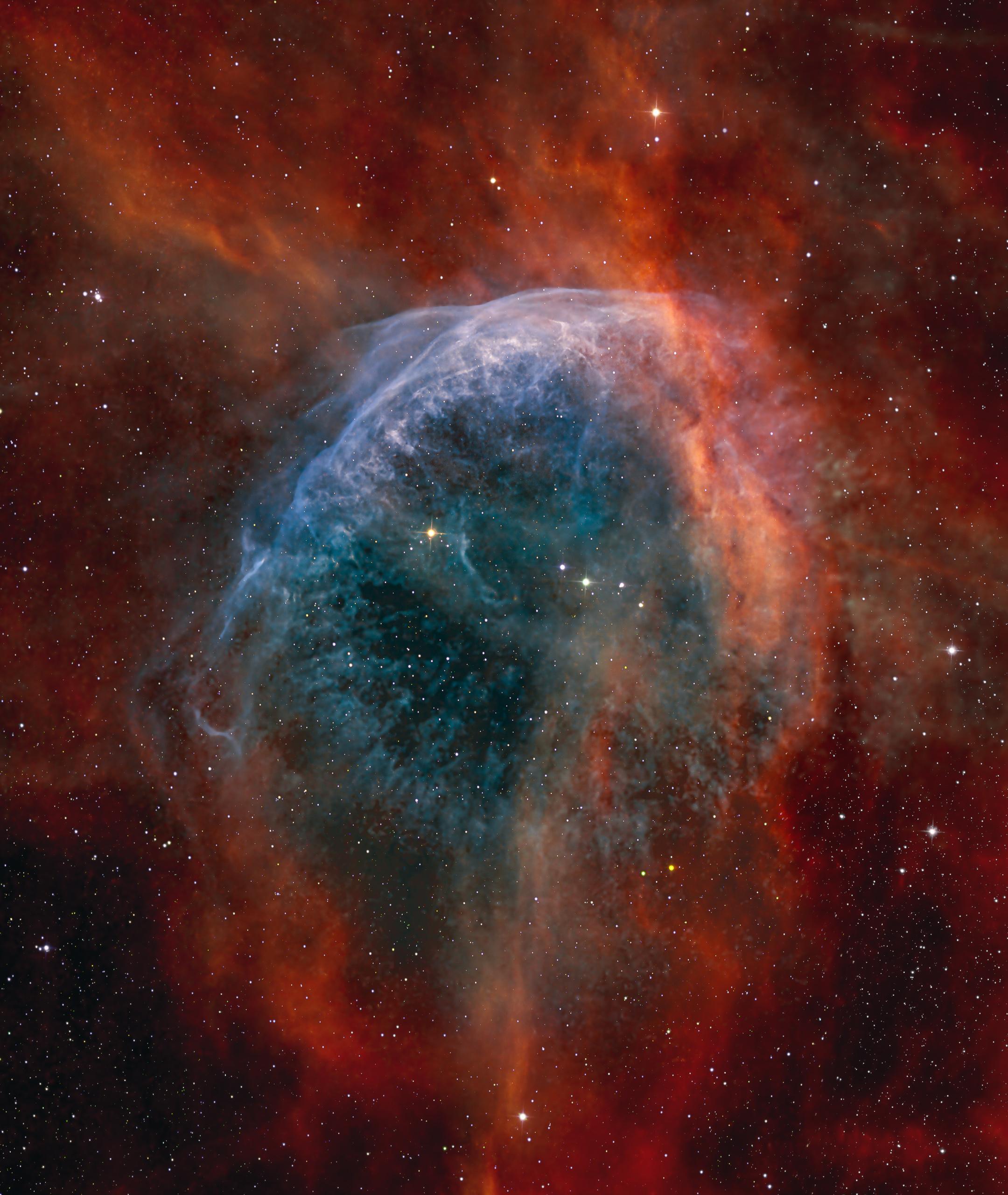 شبه فقاعة بلون مزرقّ وحولها امتدادات محمرّة بينما تتناثر نجوم عبر الصورة