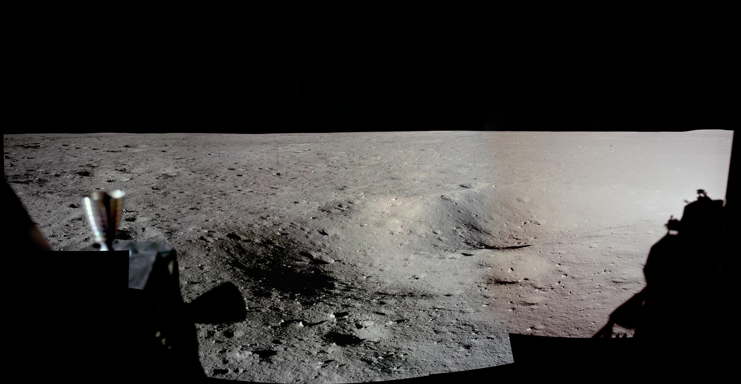 صورة پانوراميّة لسطح القمر يظهر في يمينها ظلّ مركبة وعلى اليسار فوّهات دفع وبعض التضاريس الطفيفة على السطح