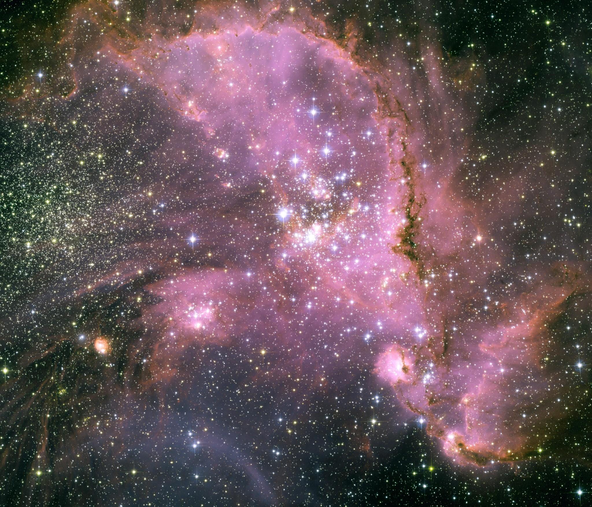 تجويف سديمي يمتدّ بلون وردي ويحوي العديد من النجوم الساطعة بينما تتناثر نجوم كثيرة أخرى على امتداد الصورة