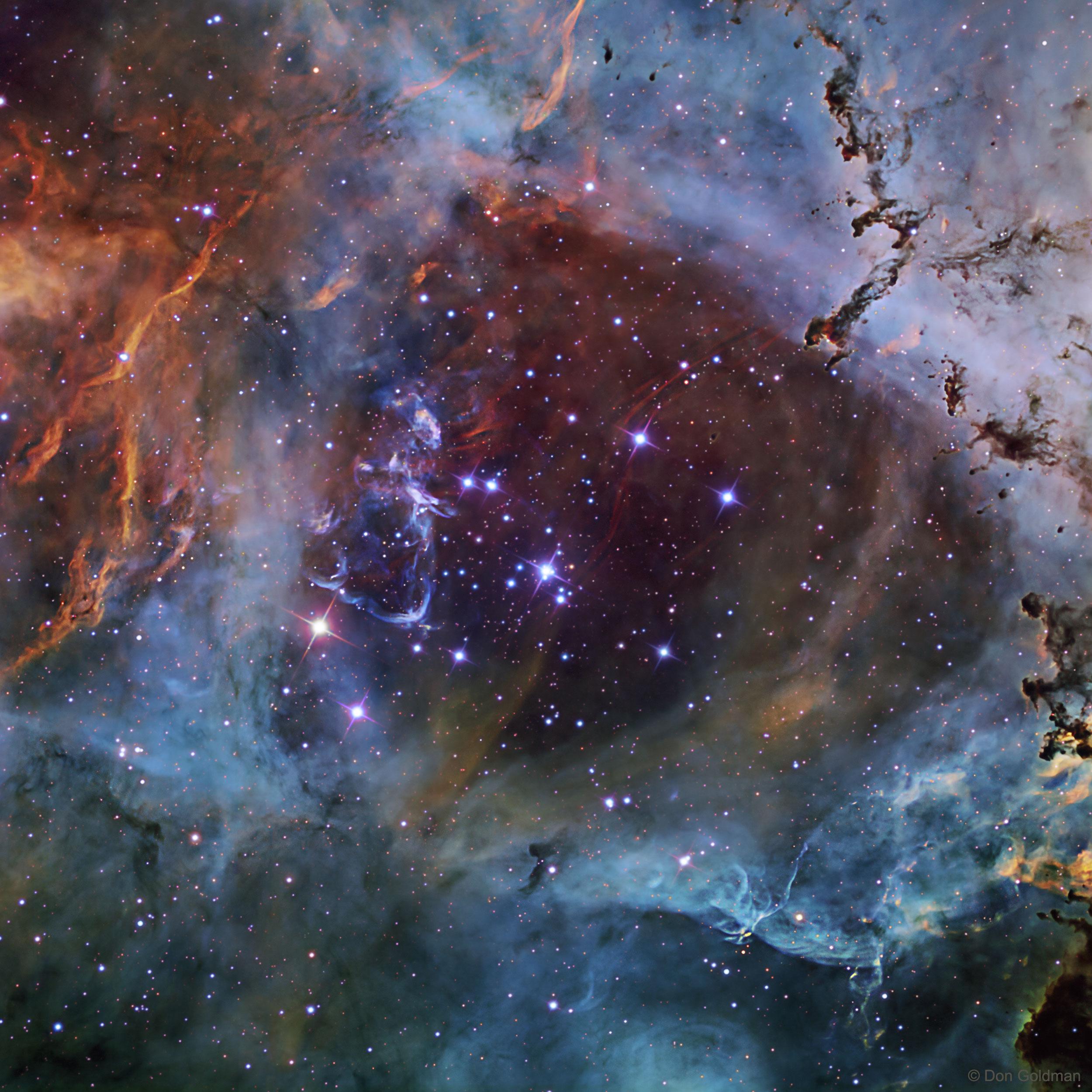 صورة تفصيليّة للعنقود النجمي الساطع الذي يقع في قلب سديم الوردة. تظهر الصورة -التي يغطيها عدد هائل من النجوم تتركّز بمعظمها حول المركز- بألوان مُبهجة محدّدة تتراوح بين الأحمر للكبريت والأخضر للهيدروجين والأزرق للأوكسجين، حيث توضّح هذه الألوان تفاصيل السديم وخيوط الغاز والغبار.