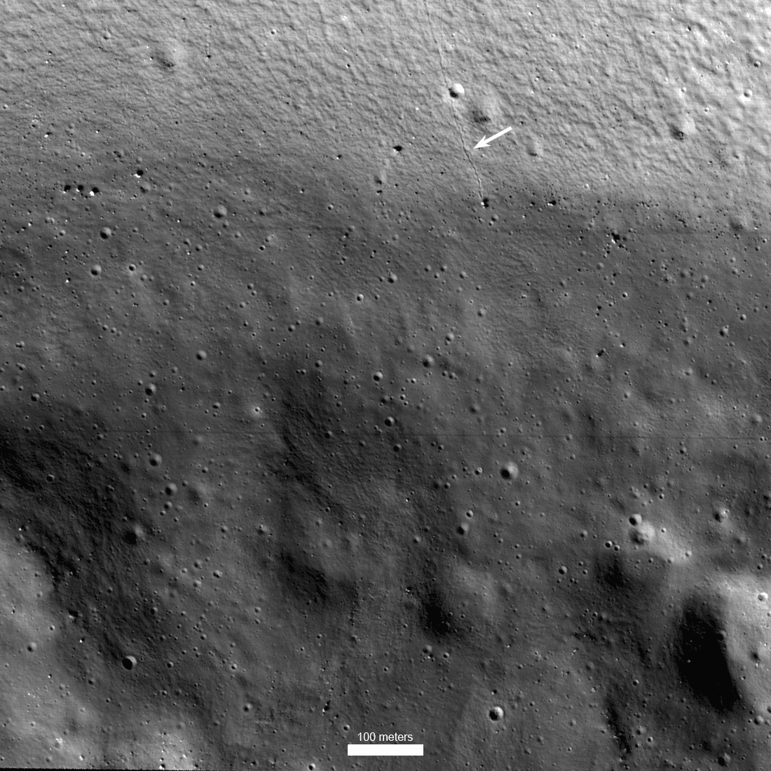 جزء مقرّب من سطح القمر يظهر تضاريس صغيرة نسبيّاً بسطوعات متدرّجة ومتباينة، مع وجود خطّ هو أثر تدحرج جلمود صخري